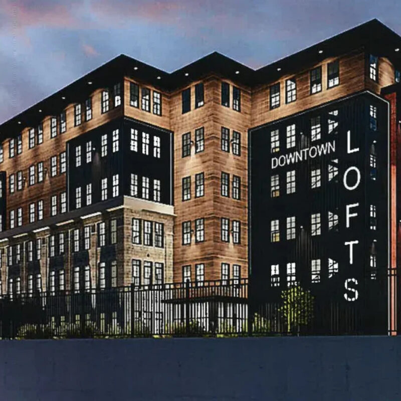 Modern loft building with "Downtown Lofts" signage, featuring a mix of architectural styles and multiple windows.