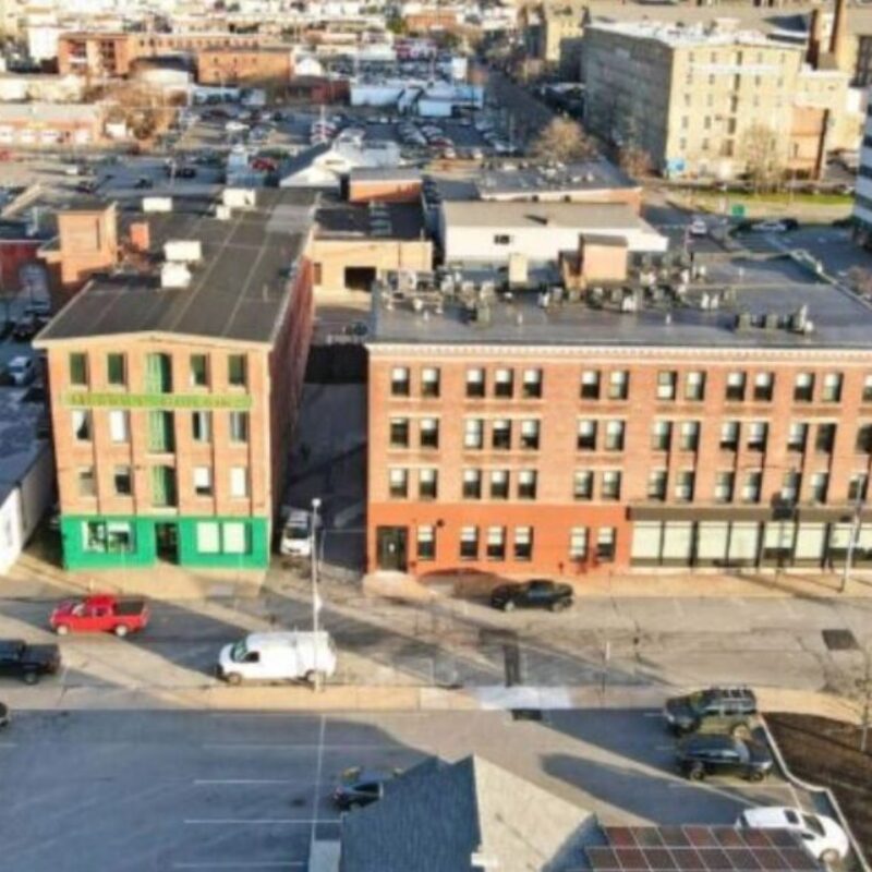 Aerial view of urban buildings, parking lots, and streets in a city setting.