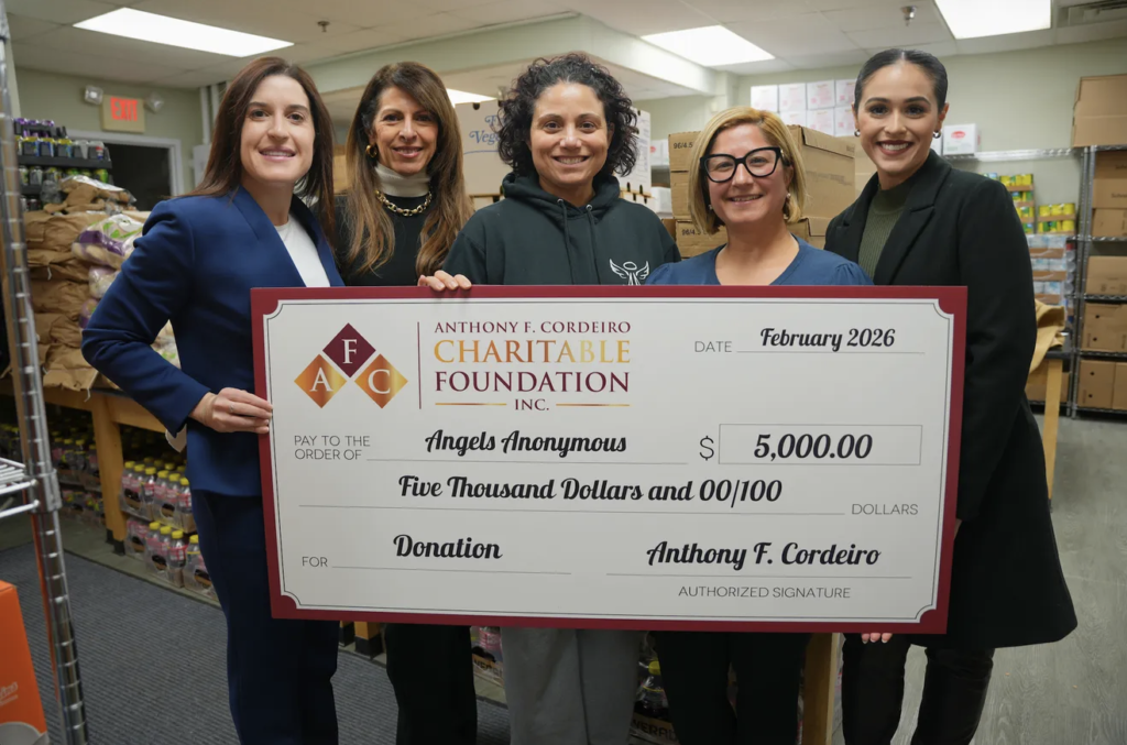 Five women hold a large check for $5,000, donating to Angels Anonymous in February 2026.