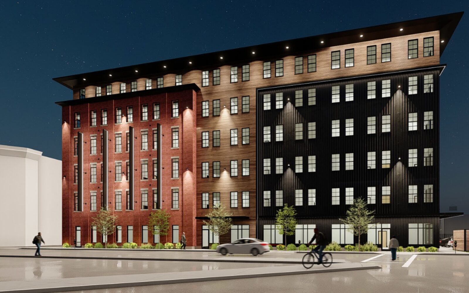 New multi-story building with a mix of brick and black siding, pedestrians and a cyclist nearby, under a night sky.