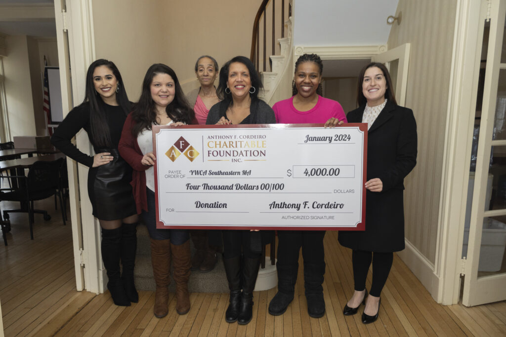 Group of six women holding a large check for $4,000, designated for YWCA Southeastern MA.