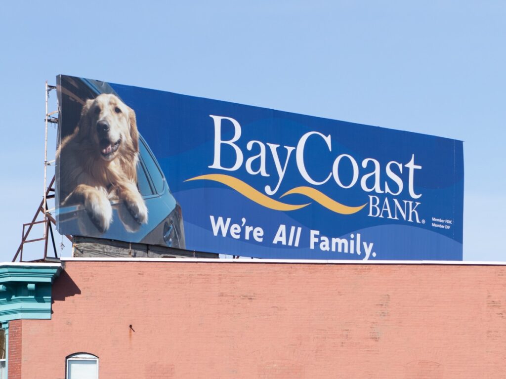 Billboard for BayCoast Bank features a smiling golden retriever and the slogan "We're All Family.