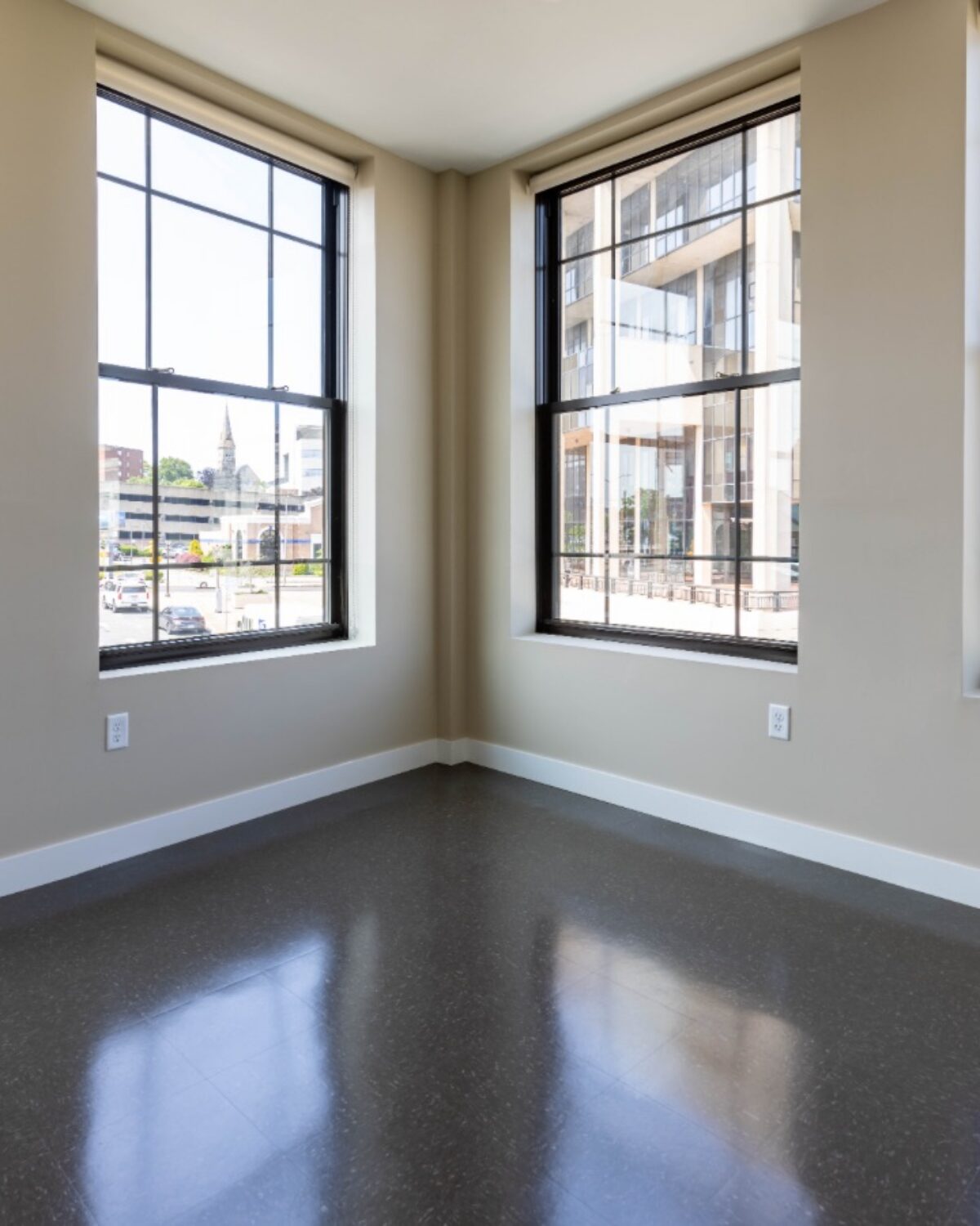 Bright room with large windows, showcasing city views and polished floor.