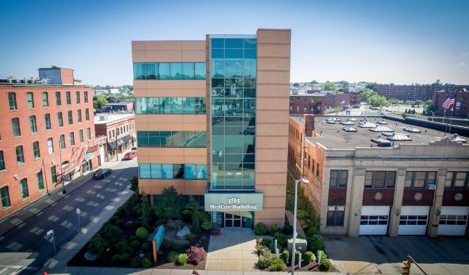 Modern glass-fronted McCon Building stands alongside older brick structures in a cityscape.