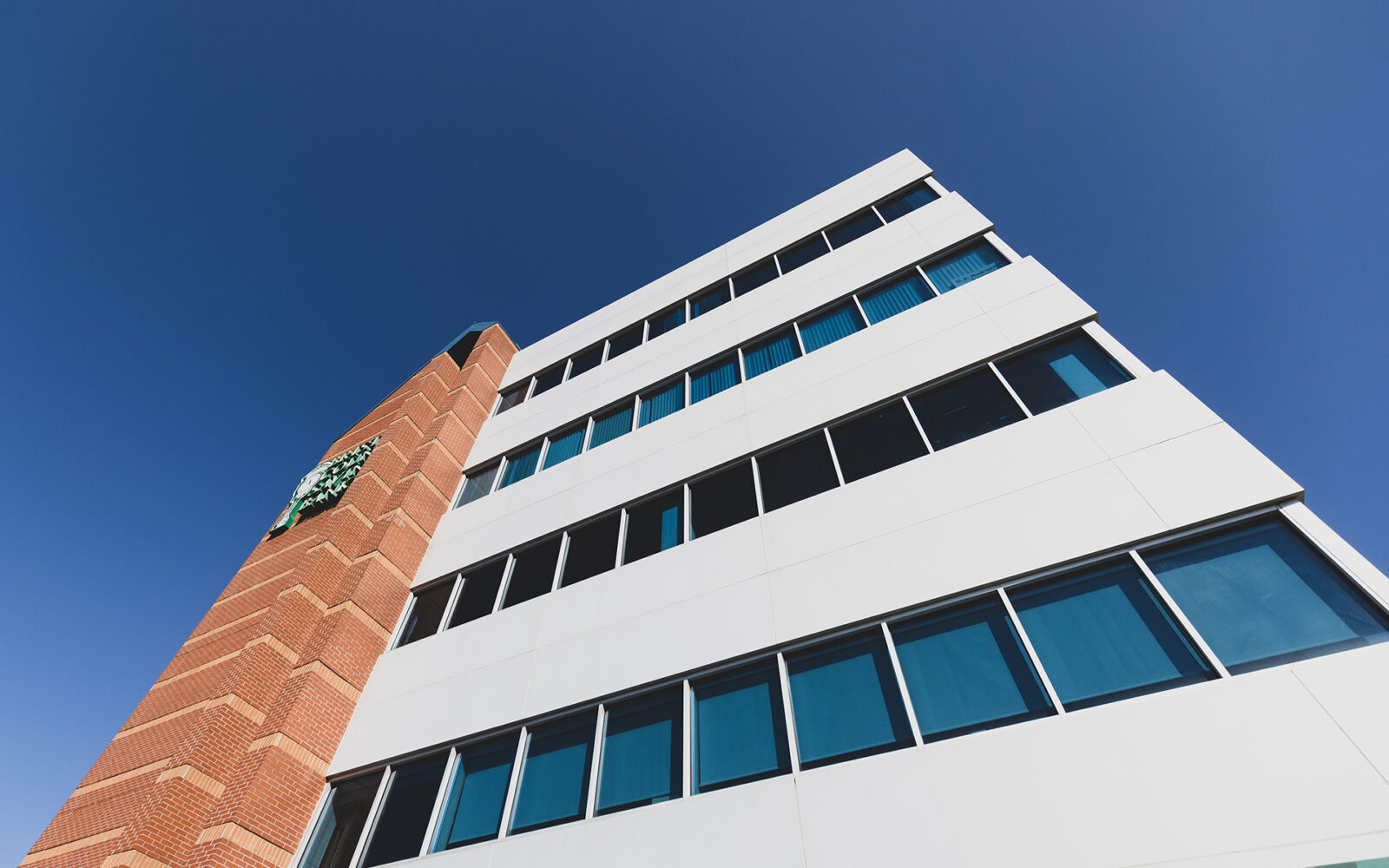 A modern bank building with a brick section and large windows against a clear blue sky.