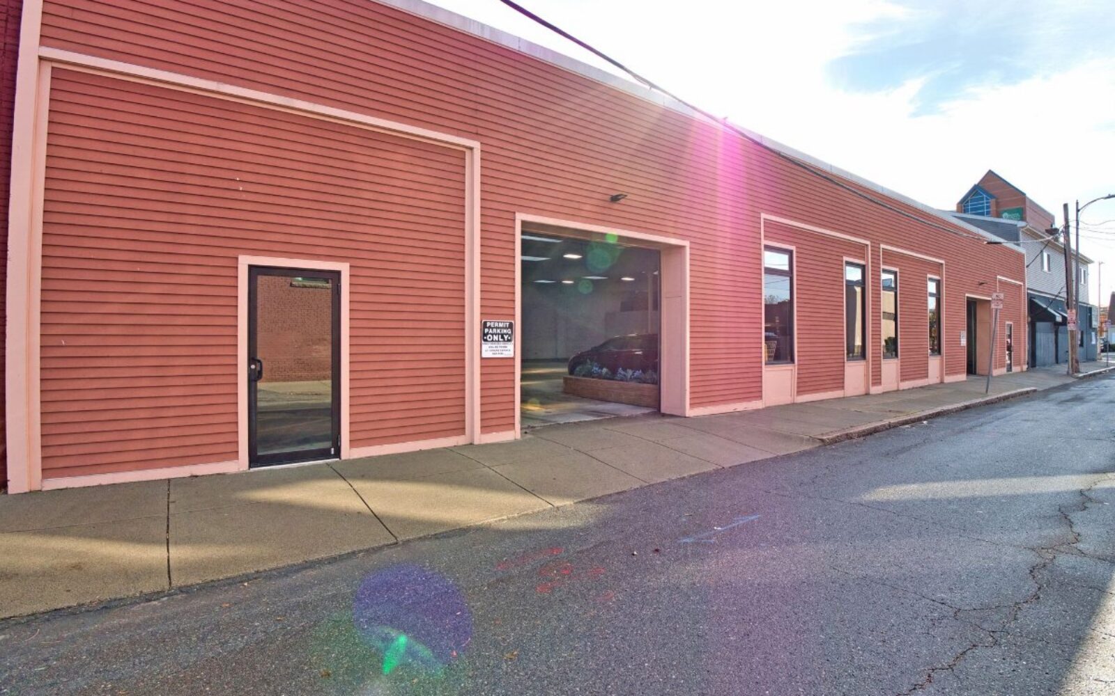 Red building exterior with large windows and a garage door, located on a city street.