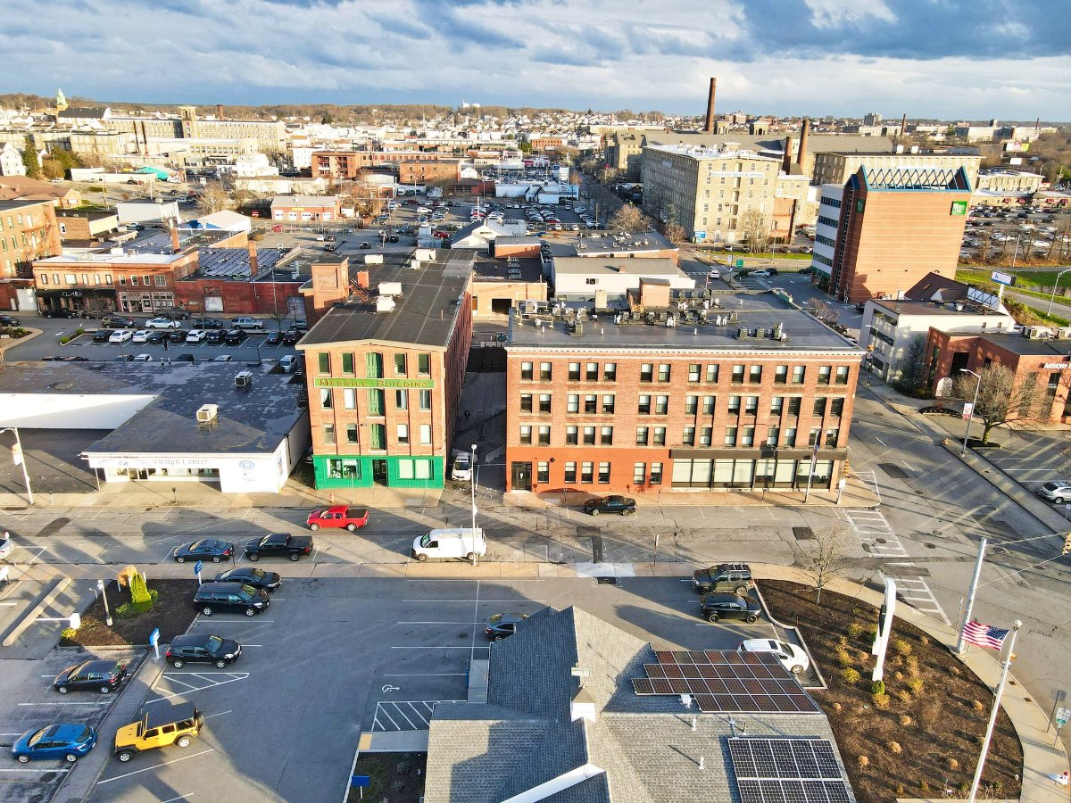 Aerial view of a city block with brick buildings, parked cars, and a mix of commercial spaces.