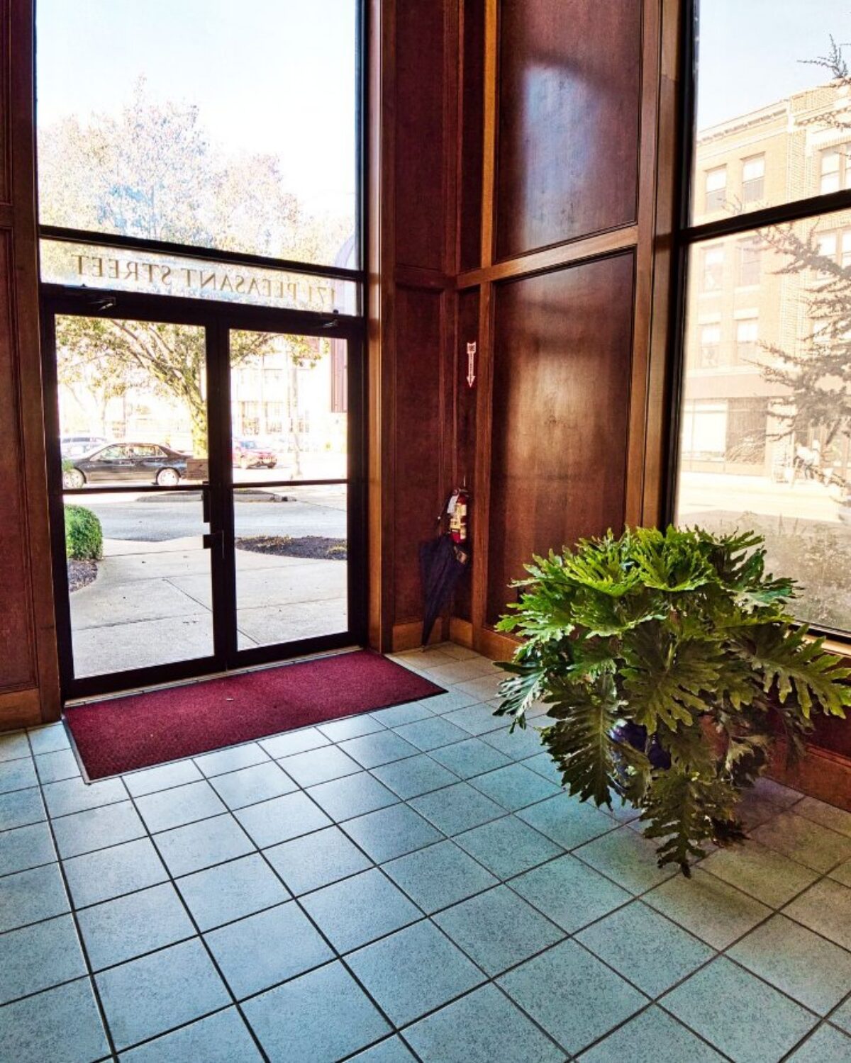 Lobby with large windows, a green plant, and a door leading to Pleasant Street.