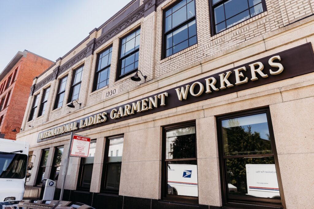Historic building with "International Ladies Garment Workers" sign, parked delivery truck, and street signage.