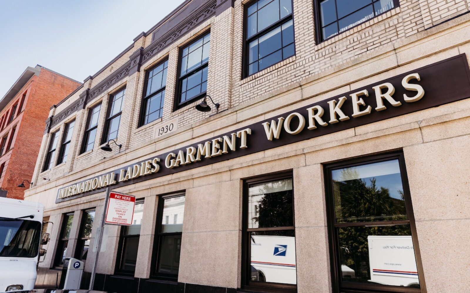 Historic building with "International Ladies Garment Workers" sign, parked delivery truck, and street signage.