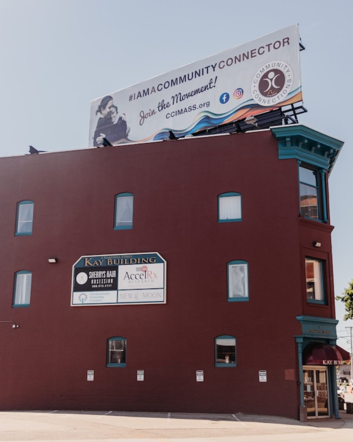 Red brick building with a blue trim, featuring a billboard and various business signs on the facade.