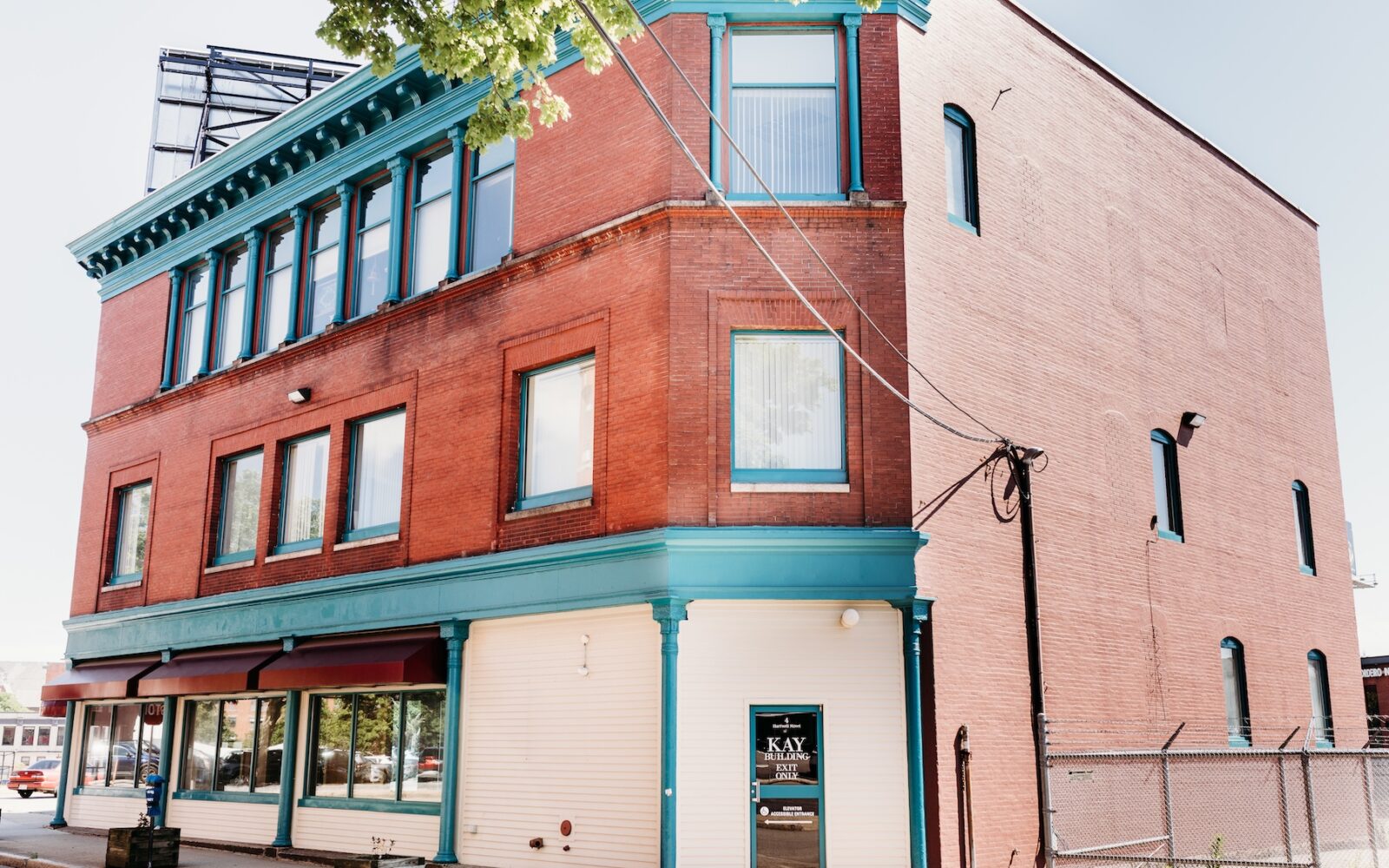 Red brick building with teal accents, large windows, and a sign for "KAY BUILDING EXIT.