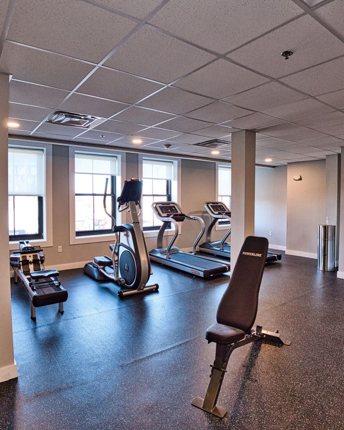A gym interior featuring exercise equipment, including treadmills, a weight bench, and fitness balls.